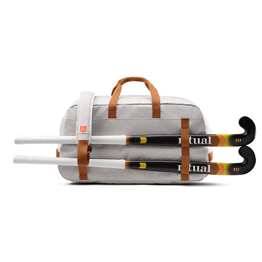 Ritual Calibre hockey duffle bag white with brown straps holding two hockey sticks, back view